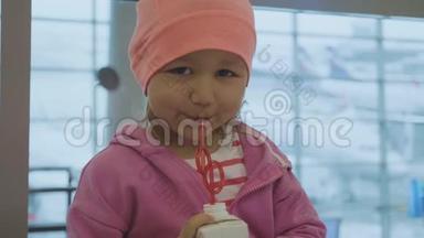 一个小孩在机场<strong>喝果汁</strong>和看镜头的肖像